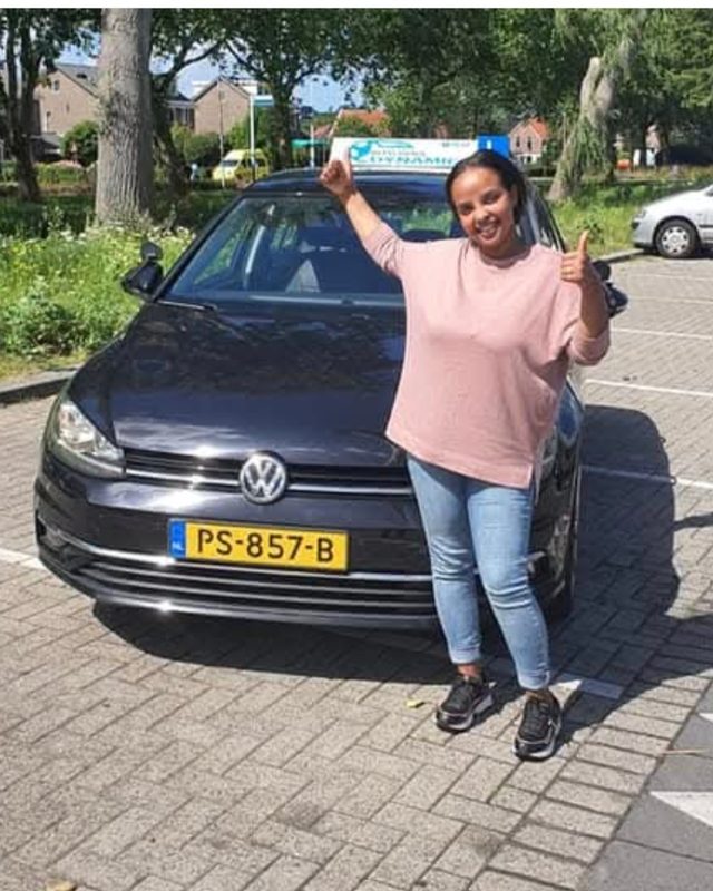 Blije leerling met haar rijbewijs bij de lesauto