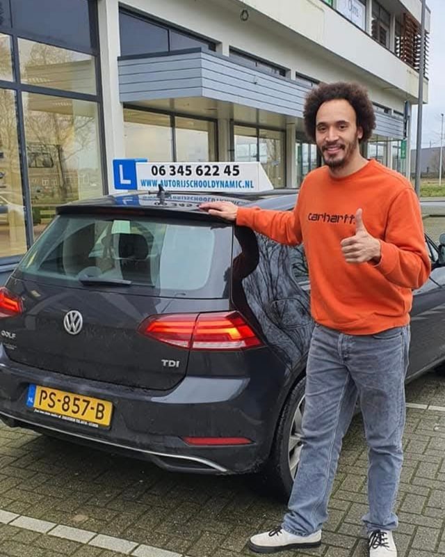 Geslaagde leerling bij de lesauto met dakbord