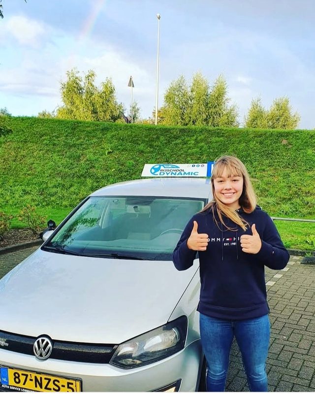 Geslaagde leerling met twee duimen omhoog bij de Polo-lesauto